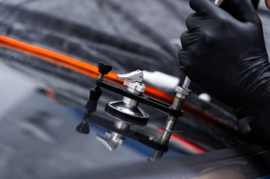 Reçine enjeksiyonuyla ön cam çatlağı onarımı. Teknisyen ön cam enjektörü kullanarak göz çatalını tamir ediyor. Yapısal berraklığı geri getirmek için enjektör uygulaması kullanarak ön camda reçine onarımı