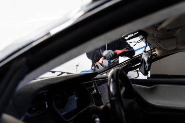 İki teknisyen vantilatör kullanarak ön cam kuruyor. Ön cam yerleştirilmesi, güvenlik ve bütünlük sağlar. Yeni ön cam kurulum süreci. Ön cam kurulumu Aspirasyon Kaldırıcıları Kullanılarak