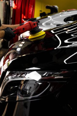 Araba kaputu sarı bloknotla parlatılıyor. Boya cilası aktif hareket halinde. Girdap izlerini silmek ve derin parlatıcıyı geri getirmek için boya parlatıcısı. Mühürleyici ya da seramik uygulama için ayrıntılı araba