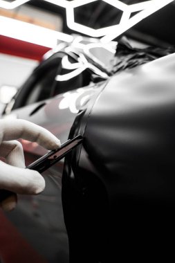 Araba sarma uygulaması araç görünümünü değiştirir. Tam panelli araba plastiği paketleme. Büyük ölçekli vinil ambalaj kurulumu aracın dış yüzeyini mat siyah film ile dönüştürür