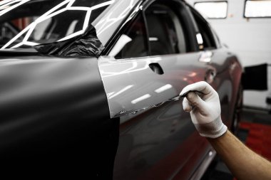 Araba sarma uygulaması araç görünümünü değiştirir. Tam panelli araba plastiği paketleme. Büyük ölçekli vinil ambalaj kurulumu aracın dış yüzeyini mat siyah film ile dönüştürür