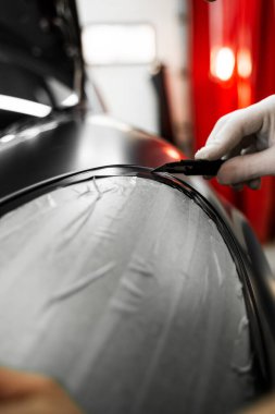 Plastik film, kusursuz araç ambalajlama sonuçları için dikkatlice uygulanır ve bıçakla budanır. Vinil ambalaj mükemmel gerilim ve kaliteli detaylar için keskin bıçak işi gerektirir.