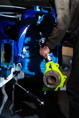 Drift Car Build için Chassis Altında Arka Süspansiyon Kurulumu. Teknisyen şasinin altındaki kol ve alt çerçeve bağlantılarını sıkılaştırıyor. Arka süspansiyon kolları şasinin altına yerleştiriliyor.