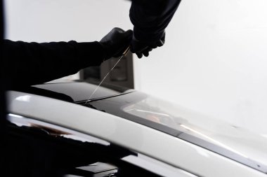 Arabanın ön camını değiştirme işlemi. Ön cam kaldırma işlemi özel kesme kablosu ve kazıma aracı kullanılarak yapılıyor. Otomobil teknisyeni ön camı ince tel ve kazıma bıçağı kullanarak ayırıyor.