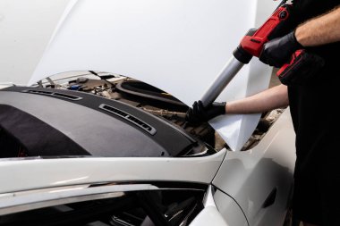 Urethane kazıma silahı, arabanın ön camının değiştirilmesinde su geçirmez bir mühür oluşturarak esnek bir yapıştırıcı uyguluyor. Bir arabanın ön camına kabartma tabancası kullanarak yapıştırıcı sürüyorum.