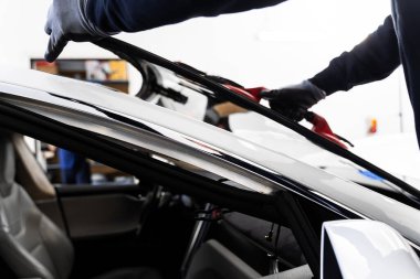 Yeni ön cam kurulum süreci. Aspirasyon asansörlerini kullanarak ön cam kurulumu. İki teknisyen vantilatör kullanarak ön cam kuruyor. Ön cam yerleştirme güvenli bir mühür ve bütünlük sağlar