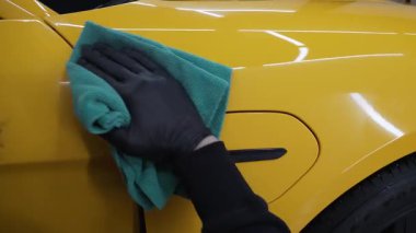 Adam araba servisi videosunda prosedürü detaylandırmadan önce arabayı mikrofiber bezle cilalıyor. Araba cilalama ve valeliğin titiz detaylandırılması.