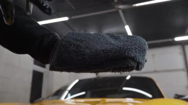 Servis videosundaki mikrofiber beze ağda yapmak için araba temizleyicisi sıvı püskürtüyor. Araba koruması için sprey ağda ürünü kullanma süreci ayrıntılandırılıyor.