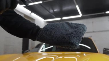 Servis videosundaki mikrofiber beze ağda yapmak için araba temizleyicisi sıvı püskürtüyor. Araba koruması için sprey ağda ürünü kullanma süreci ayrıntılandırılıyor.