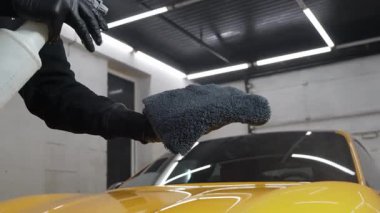 Servis videosundaki mikrofiber beze ağda yapmak için araba temizleyicisi sıvı püskürtüyor. Araba koruması için sprey ağda ürünü kullanma süreci ayrıntılandırılıyor.