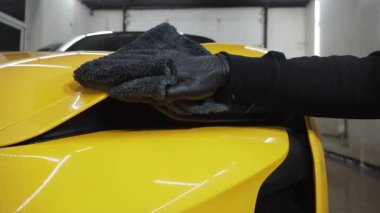 İşçi, araba farı cilası için 4K video kullanıyor. Serviste mikrofiber bezle far parlatma işlemi spor araba detaylandırması.