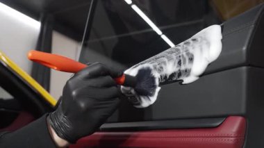 Araba temizleyicisi otomatik kapıyı köpük fırça ve deterjan 4K video ile temizliyor. Araba yıkama yerindeki araba kapısındaki toz ve kiri temizleme işlemi..