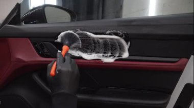 4K videosundaki araba kapısındaki toz ve kiri kaldırma işlemi. Araba temizleyicisi araba kapısını köpük fırça ve deterjanla temizliyor..