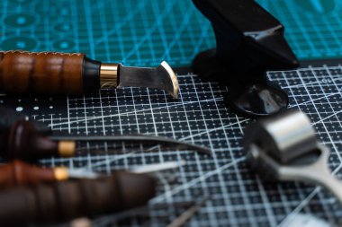 Traditional wooden-handled awls and cutters beside a small anvil illustrate timeless craftsmanship and dedication to bespoke design. Leathercraft Tools on Workbench