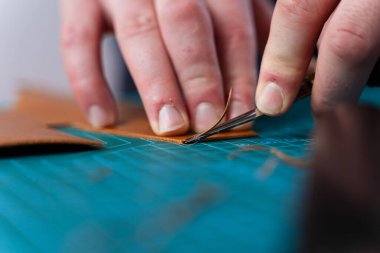 Deri kenarları aletle buduyorum. Zanaatkar, deri kenarları hassas aletlerle keser ve kesiği rafine eder. Sanatçı, pürüzsüz kıvrımlar ve temiz hatlar sağlayan, budama aracı ile deri kenarları rafine eder