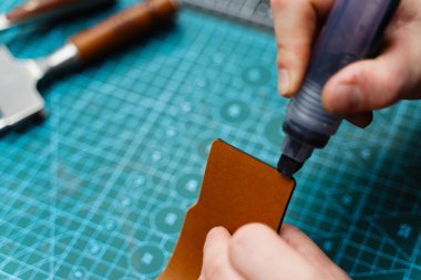 Boyama işaretiyle bitiş çizgisinde. Esnaf deri parçasına kenar boyası sürerek dayanıklılığını arttırıyor. Zanaatkar koyu kenarı deri kesimine uygular. Güç, pürüzsüzlük ve incelik ekler.