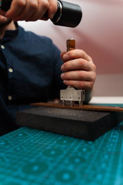 Deri kayışlı yumruk aletleriyle kemer delikleri açmak. Deri kemer deliklerini yumruklamak ve detaylandırmak. Zanaatkar, yeşil bir paspasın el yapımı kemeri için deri kayışlara delikler açıyor.