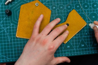 Deri ustaları dikiş atmadan önce kenar hazırlamak için yapıştırıcı kullanır. Deri kenarlara yapıştırıcı sürüyorum. Deri ürünler üretimi güçlü yapıştırıcıları güvenli bir şekilde yapıştırmakla başlar.