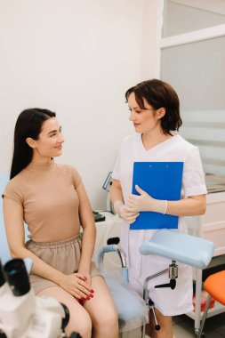 Jinekolog, klinikteki hastasıyla birlikte teşhis bulgularını inceliyor. Jinekolog, Pap test sonuçlarını hastasıyla tartışıyor.