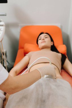 Jinekolog, sakin bir hastaya karın ultrasonu uygular. Karın ultrasonu. Jinekolog üreme sağlığı değerlendirmesi için ultrason cihazı kullanıyor.