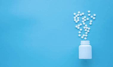 white pills and blue tablets on a light background. copy space.