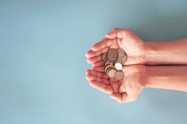 Mavi arka planda bozuk para tutan eller