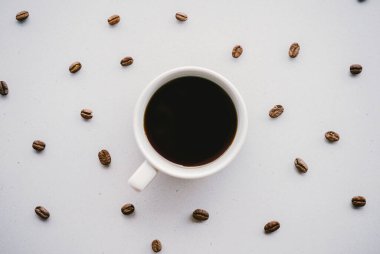 Fotokopi alanı olan beyaz bir arka planda kahve çekirdekli bir fincan görüntüsü.