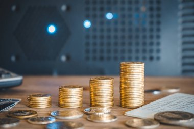Tahta masa, işletme ve finans konsepti üzerinde madeni paralar, hesap makinesi ve bilgisayar klavyesi yığını.