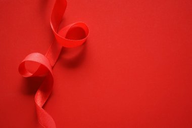 Kırmızı arka planda kırmızı ipek kurdele. düz yatış, üst görünüm.