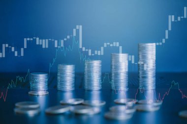 Tablo üzerinde grafik ve grafik olan bozuk para yığını.