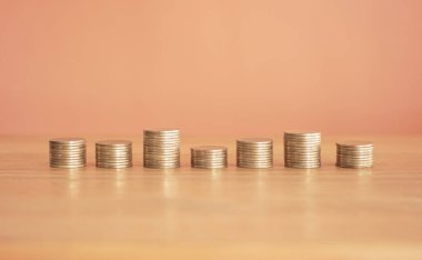 Tahta bir masanın üzerinde bir yığın bozuk para ve bir yığın dolar. kaydetme kavramı