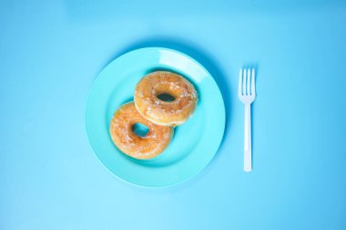 donut ve donut mavi bir tabakta mavi arka planda.