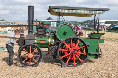Tarrant Hinton. Dorset. Birleşik Krallık. 25 Ağustos 2022. 1980 'lerde yapılmış bir Wallis ve Steevens çekiş motorunun kopyası Büyük Dorset Buhar Fuarı' nda bir harman makinesi kullanıyor.