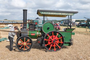 Tarrant Hinton. Dorset. Birleşik Krallık. 25 Ağustos 2022. 1980 'lerde yapılmış bir Wallis ve Steevens çekiş motorunun kopyası Büyük Dorset Buhar Fuarı' nda bir harman makinesi kullanıyor.