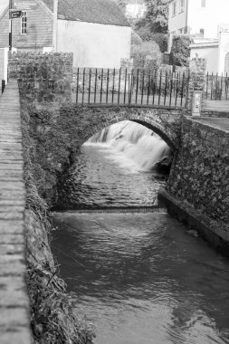 Dorset 'teki Lyme Regis' teki Lim nehri geçidinde bir köprünün altından akan uzun bir su akıntısı..