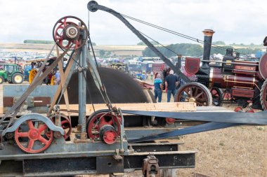 Tarrant Hinton. Dorset. Birleşik Krallık. 25 Ağustos 2022. 1909 model Burrell vinç motoru Büyük Dorset Buhar Fuarı 'nın arka planında çalışırken eski moda bir daire testere ile kereste kesiliyor.