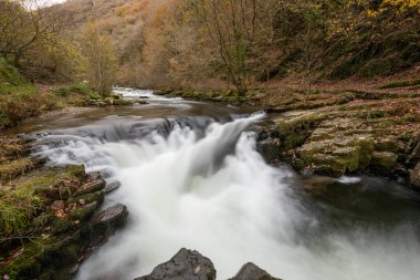 Long exposure of the Watersmeet Bridge waterfall on the East Lyn river at Watersmeet In Exmoor National Park in autumn