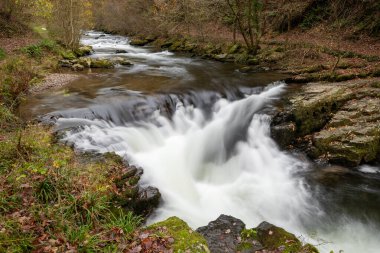 Long exposure of the Watersmeet Bridge waterfall on the East Lyn river at Watersmeet In Exmoor National Park in autumn