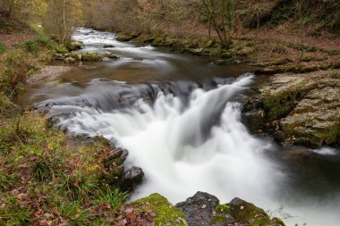 Long exposure of the Watersmeet Bridge waterfall on the East Lyn river at Watersmeet In Exmoor National Park in autumn