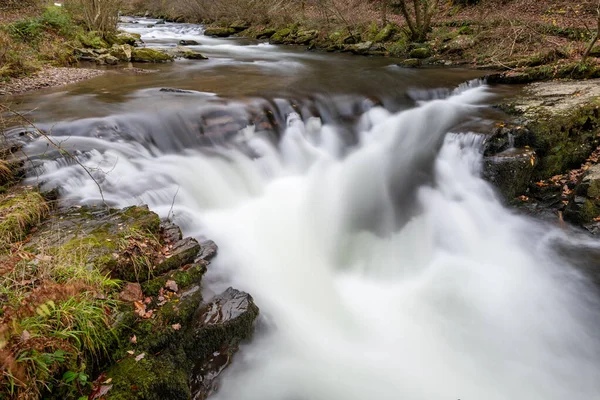 Long exposure of the Watersmeet Bridge waterfall on the East Lyn river at Watersmeet In Exmoor National Park in autumn