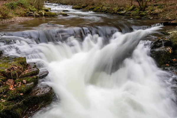 Long exposure of the Watersmeet Bridge waterfall on the East Lyn river at Watersmeet In Exmoor National Park in autumn