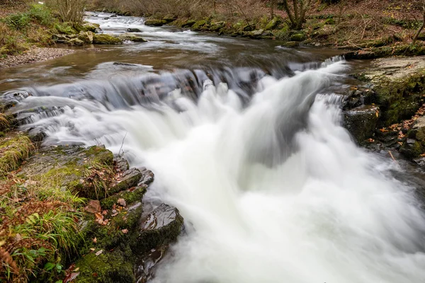 Long exposure of the Watersmeet Bridge waterfall on the East Lyn river at Watersmeet In Exmoor National Park in autumn