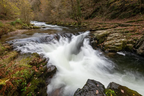 Long exposure of the Watersmeet Bridge waterfall on the East Lyn river at Watersmeet In Exmoor National Park in autumn