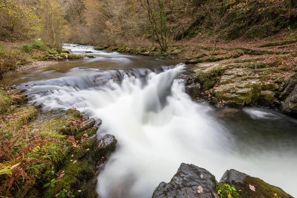 Long exposure of the Watersmeet Bridge waterfall on the East Lyn river at Watersmeet In Exmoor National Park in autumn