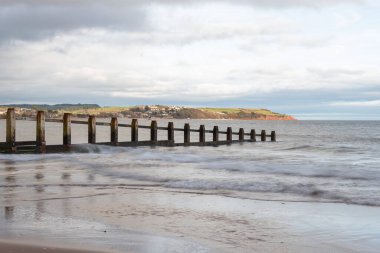 Landscape photo of a groyne in the sea at Dawlish Warren nature reserve with Exmouth in the background