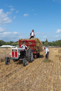 Drayton. Somerset. Birleşik Krallık. 19 Ağustos 2023. İzleyiciler, David Brown Selectamatic 990 tarafından çekilen bir karavana saman yığını yüklüyorlar.