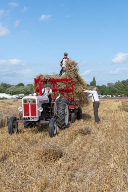 Drayton. Somerset. Birleşik Krallık. 19 Ağustos 2023. İzleyiciler, David Brown Selectamatic 990 tarafından çekilen bir karavana saman yığını yüklüyorlar.