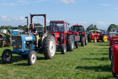 Drayton. Somerset. Birleşik Krallık. 19 Ağustos 2023 Klasik ve klasik traktörlerden oluşan bir seçim, Dünden kalma bir çiftçilik etkinliğinde arenaya girmek için sıraya giriyor.