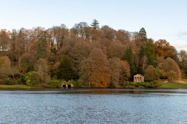 Wiltshire 'daki Stourhead bahçesindeki gölün etrafındaki sonbahar renklerinin görüntüsü