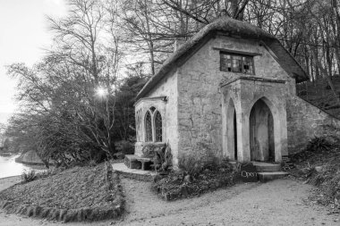 Wiltshire 'daki Stourhead Bahçeleri' ndeki Gotik Kulübe 'nin arkasında güneşin batışının siyah beyaz fotoğrafı.